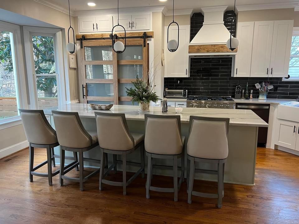 Kitchen remodel with white shaker cabinets, black subway tile backsplash, timber barn doors and a marble-topped island with five stools
