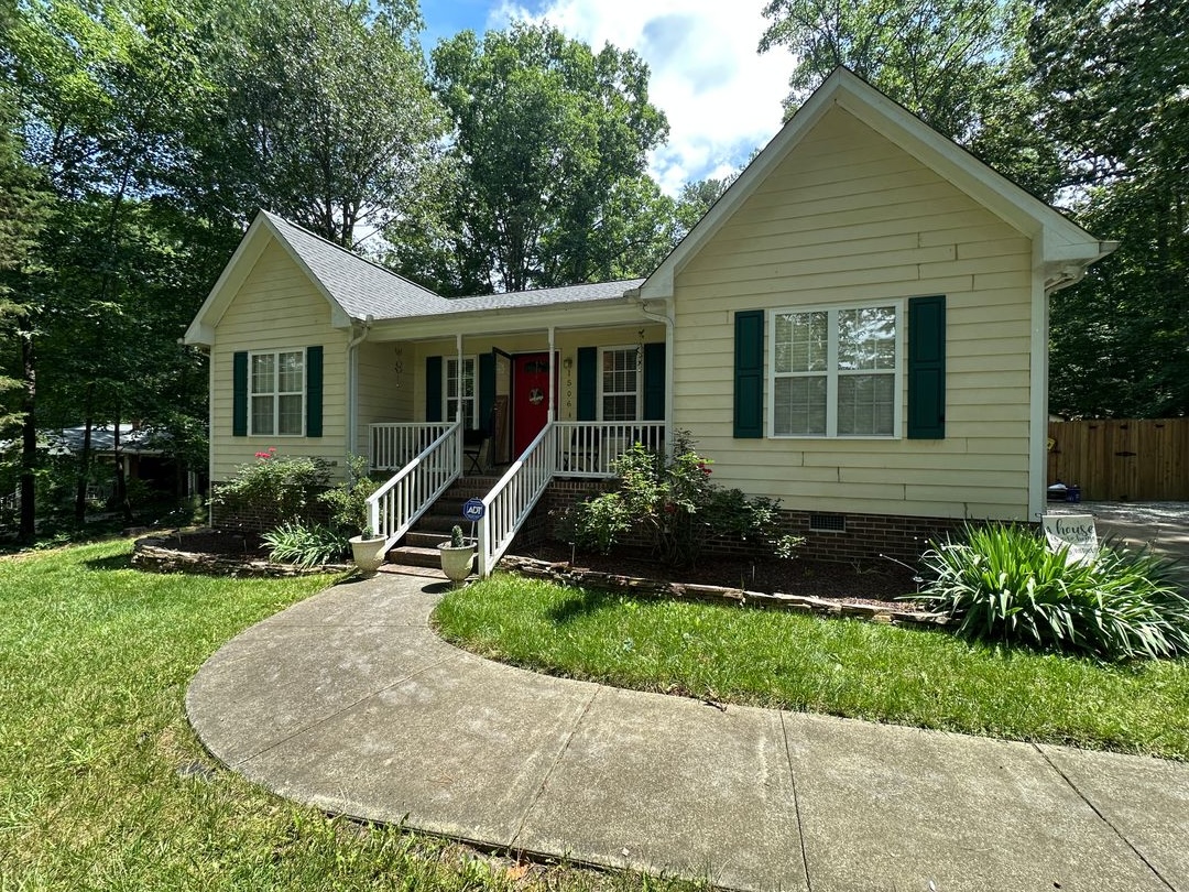 Exterior of a single-storey home with a covered front porch, shutters and mature planting, remodeled throughout